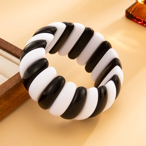Macro view of chunky irregular black and white spiral resin cuff with polished finish