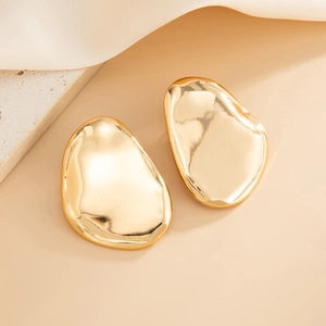 Detailed close-up of golden irregular organic stud earrings with a high-polished mirror finish
