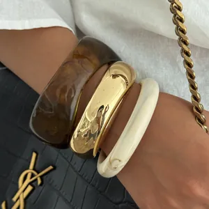 Detailed close-up of a three-piece set with gold metal and textured resin bangles