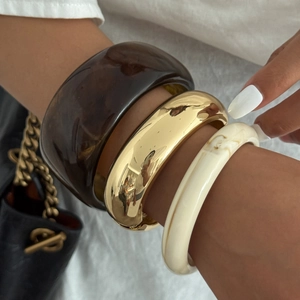 Dettaglio del set di tre bracciali in resina marrone, metallo dorato e trama marmo