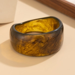 Vista dettagliata di un ampio bracciale in resina tartarugata ambra con texture liscia
