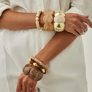 Set di bracciali larghi in acrilico con trama marmorizzata e dettagli dorati su modella