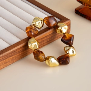 Detail of amber resin and irregular golden metallic beads on a minimalist necklace