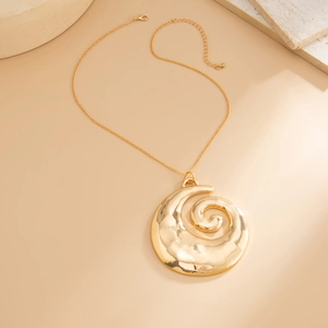 Makro-Detail des goldenen Spiralblüten-Anhängers mit Hammerschlag-Textur auf Minimal-Stein