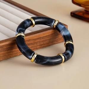Detail of beaded resin bracelet with gold spacers leaning on a wooden jewelry box