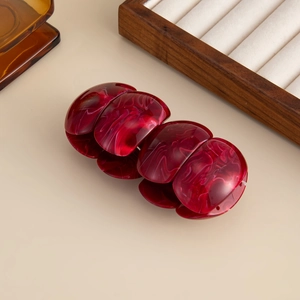 Macro detail of wine red marble resin hair claw clip with glossy finish on wooden background
