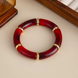 Detaillierte Draufsicht auf Retro-Armreif aus rotem Acryl mit eleganten Goldmetallringen