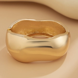 Close-up of golden irregular wavy cuff bracelet with polished finish and hinge