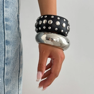 Détail du bracelet punk large en cuir à clous argentés et jonc en argent poli brillant