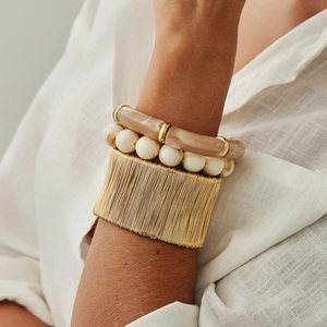 Dettaglio di un bracciale dorato con resina marmorizzata e perline color crema