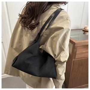 Minimalist black suede tote bag with long straps shown in a lifestyle commuter scene