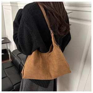 Detail einer braunen Wildleder-Tragetasche mit matter Textur und schlichtem Schultergurt