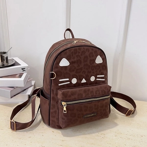 Detail of leopard print backpack featuring cute white cat face embroidery and gold zipper