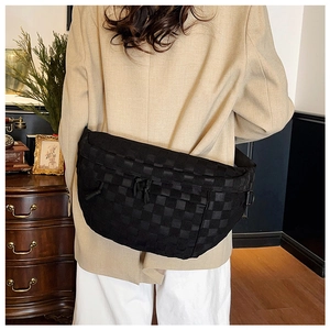 Detail of black crossbody chest bag featuring woven texture and adjustable drawstrings