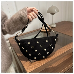 Detail of black suede crescent bag with gold rivet studs and adjustable strap