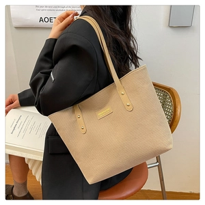 Detail of corduroy tote bag featuring a leather fashion label and sturdy metal rivets