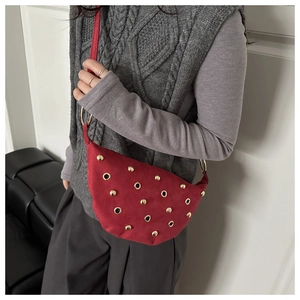 Detail of red crescent shoulder bag with golden studs and metal rings decoration