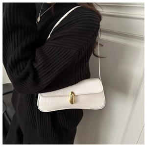 Detail of white crocodile pattern shoulder bag with elegant golden oval metal clasp closure