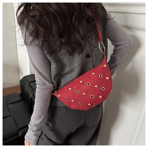 Detail of red suede crescent bag with gold studs and large metallic ring connectors