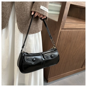 Detail view of glossy black shoulder bag with dual front pockets and silver hardware
