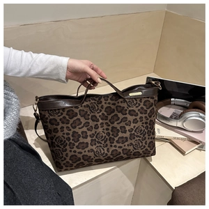Detail of leopard and rose print tote bag with brown leather handles and gold brand tag