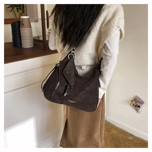 Detail der dunkelbraunen Wildleder-Hobo-Tasche mit passender kleiner Dreieckstasche