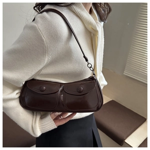 Detail of dark brown glossy leather baguette bag with dual front flap pockets