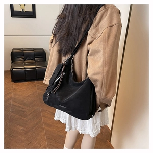 Détail du sac hobo noir porté avec mini pochette et bandoulière en cuir noir