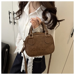 Vue détaillée de la texture en cuir marron et du logo gaufré sur le sac vintage
