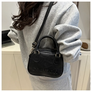 Model wearing black crossbody bag with COIH-2DN embossed texture and top handle