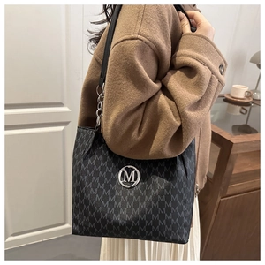 Détail d'un sac cabas noir à monogramme avec logo M argenté porté par un mannequin