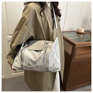 Silver-grey large tote bag in wrinkled metallic fabric worn over an olive trench coat