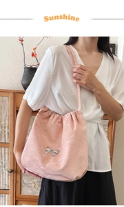 Dettaglio borsa tote in raso rosa con chiusura a coulisse e fiocco in metallo argento