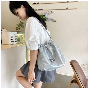 Dettaglio borsa tote argento metallizzato con coulisse e fiocco in un ambiente casual