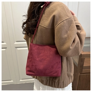 Detail view of burgundy suede crossbody bag with fashion and classic embossed text