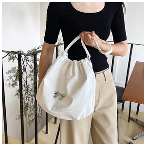 Dettaglio della borsa tote bianca con coulisse, fiocco in metallo argento e finitura lucida