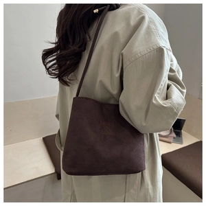Detail of dark brown matte bucket bag with embossed fashion and classic text on textured leather