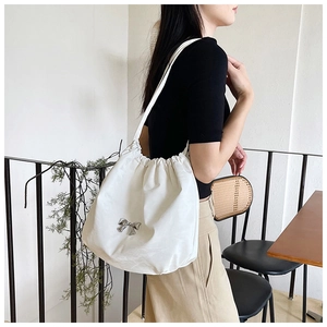Dettaglio della borsa tote bianca a coulisse con decorazione a fiocco in metallo