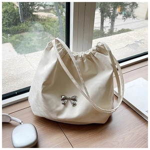 Dettaglio della borsa tote crema con fiocco in metallo argento e chiusura a coulisse