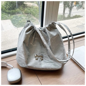 Primo piano della borsa a secchiello argento con texture stropicciata e fiocco metallico