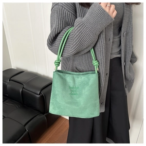 Close-up of mint green suede bucket bag featuring fashion embroidery and knotted handle