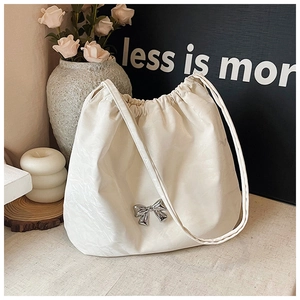 Dettaglio ravvicinato della borsa con coulisse bianco crema con fiocco in metallo argento