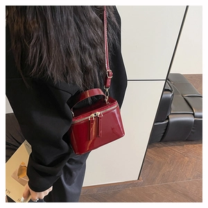 Detail of red patent leather vanity bag with metal double zipper and rigid box structure