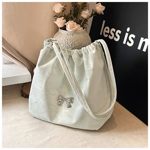 Dettaglio di una borsa tote verde menta con coulisse e un elegante fiocco in metallo argento