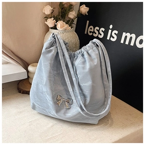 Dettaglio della borsa tote azzurra con fiocco metallico, coulisse e trama plissettata