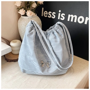 Dettaglio borsa tote azzurra con coulisse e decorazione a fiocco in metallo lucido