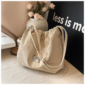 Dettaglio borsa tote beige con chiusura a coulisse, trama marmo e fiocco d'argento