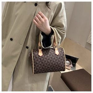 Detail of Boston bag with geometric windmill pattern held by model in trench coat