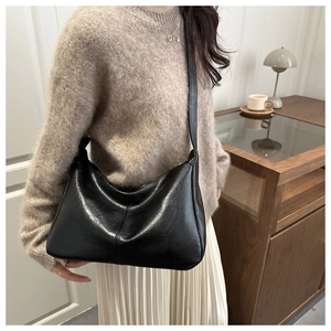 Close-up of a black half-moon shoulder bag with retro stitching on premium oil-wax leather
