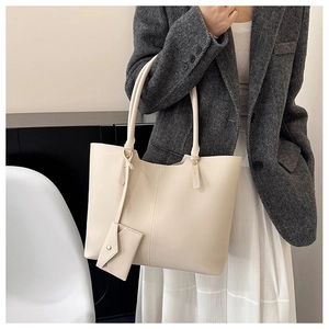 Off-white large tote bag with matching mini envelope pouch worn with a grey blazer